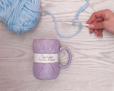 En lilla kaffekopp som er formet som et garnøste med teksten crocheter one armed hooker. Helt perfekt til alle som elsker å hekle, og en veldig morsom gave til jul eller bursdag