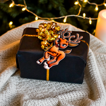 Reinsdyr til og fra lapp til julegavene som festes i gavebåndet rundt julegaven. Gavelappen er i boble effekt og skiller seg ut fra vanlige gavelapper. Man får følelsen av en 3d effekt. Her ligger gaven på et teppe med juletreet i bakgrunnen. Skriv hvem gaven er til og fra på baksiden av lappen. 