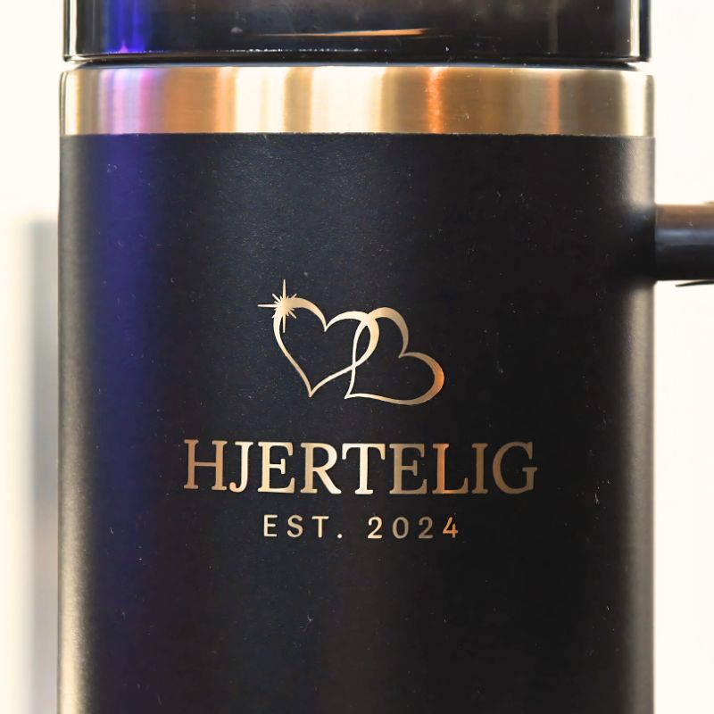 Nærbilde av logo og gull kant. Lasergravert gulldetaljer som skiller denne drikkeflasken fra andre kopper og gjør den et lett valg når man skal kjøpe gave til noen. Dette er en julegave man faktisk kommer til å bruke. Kvaliteten kjenner man på med en gang man holder i den. Den føles tyngre og bedre kvalitet enn de billige flaskene man kan få tak i. 