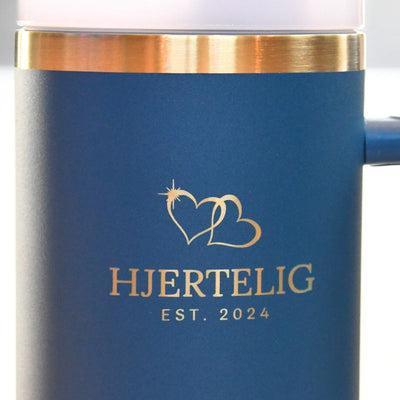 Nærbilde av hjertelig logoen og gullkanten på termokoppen. 