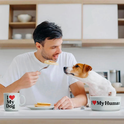 Hundeskål og kaffekopp i bruk. Mannen på bilde spiser, og hunden sitter ved siden av og stirrer på maten.