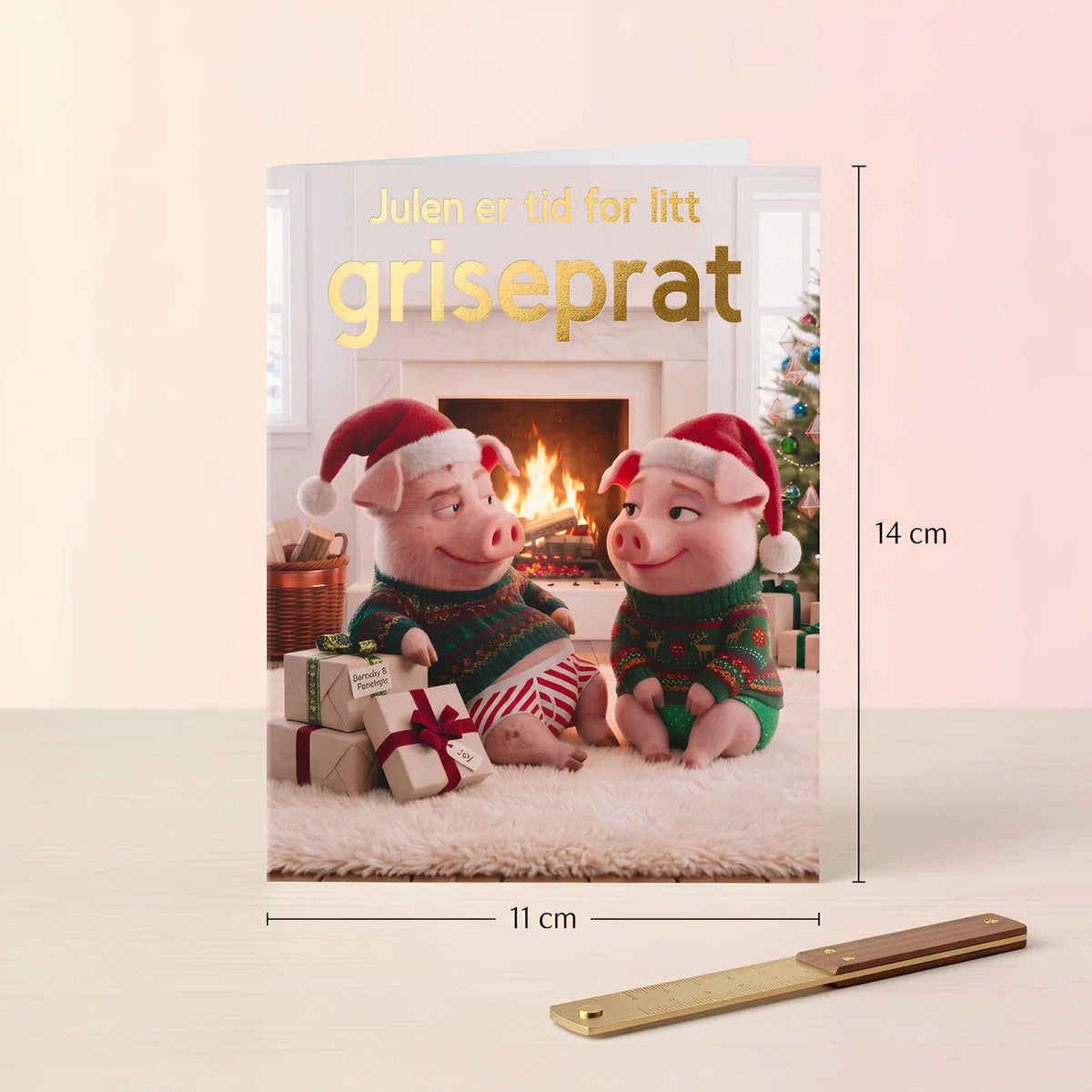 Julekortet med grisene vist med mål. Det doble brettekortet er 11 cm bredt og 14 cm høyt, her sammen med en gullpenn.