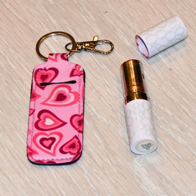 Rosa veske til lipstick man kan henge på ting på bakken. Vesidenav ligger det en åpen lipstick