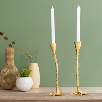 Long legs lysestaker som står på en benk med grønn vegg bak seg og noen blomster. Unikt og eksklusivt dekor med nydelige gulldetaljer. Strutsebein som gjør hjemmet ditt unikt og et eksklusivt inntrykk. 