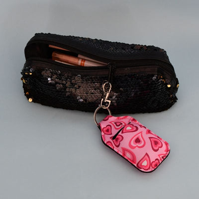 Veske til airpodsene med rosa hjerter på seg som henger på et åpent penal. 