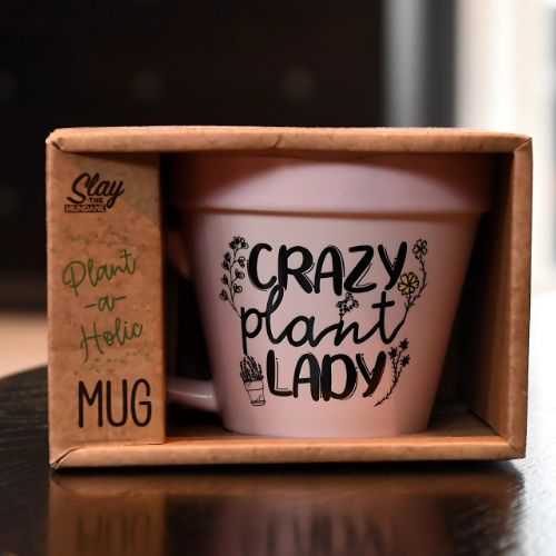 Rosa plantekopp med humor. På koppen står det "Crazy plant lady". Her er koppen inni esken sin. 