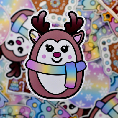 Gavelapp med reinsdyr motiv. Reinsdyret har et pastell skjerf på seg og ser ut som en runding. En tegneseriefigur med flotte farger. Disse til og fra lappene gir julegavene det lille ekstra og skiller seg ut fra de tradisjonelle lappene man finner i butikken. Fest gavebåndet i øret til reinsdyret og skriv hvem gaven er til og fra på baksiden. 