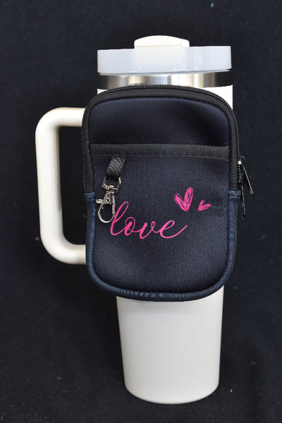 En sort liten ryggsekk med rosa love tekst og to hjerter som er festet på en termokopp. Brukes til å oppbevare småsaker.