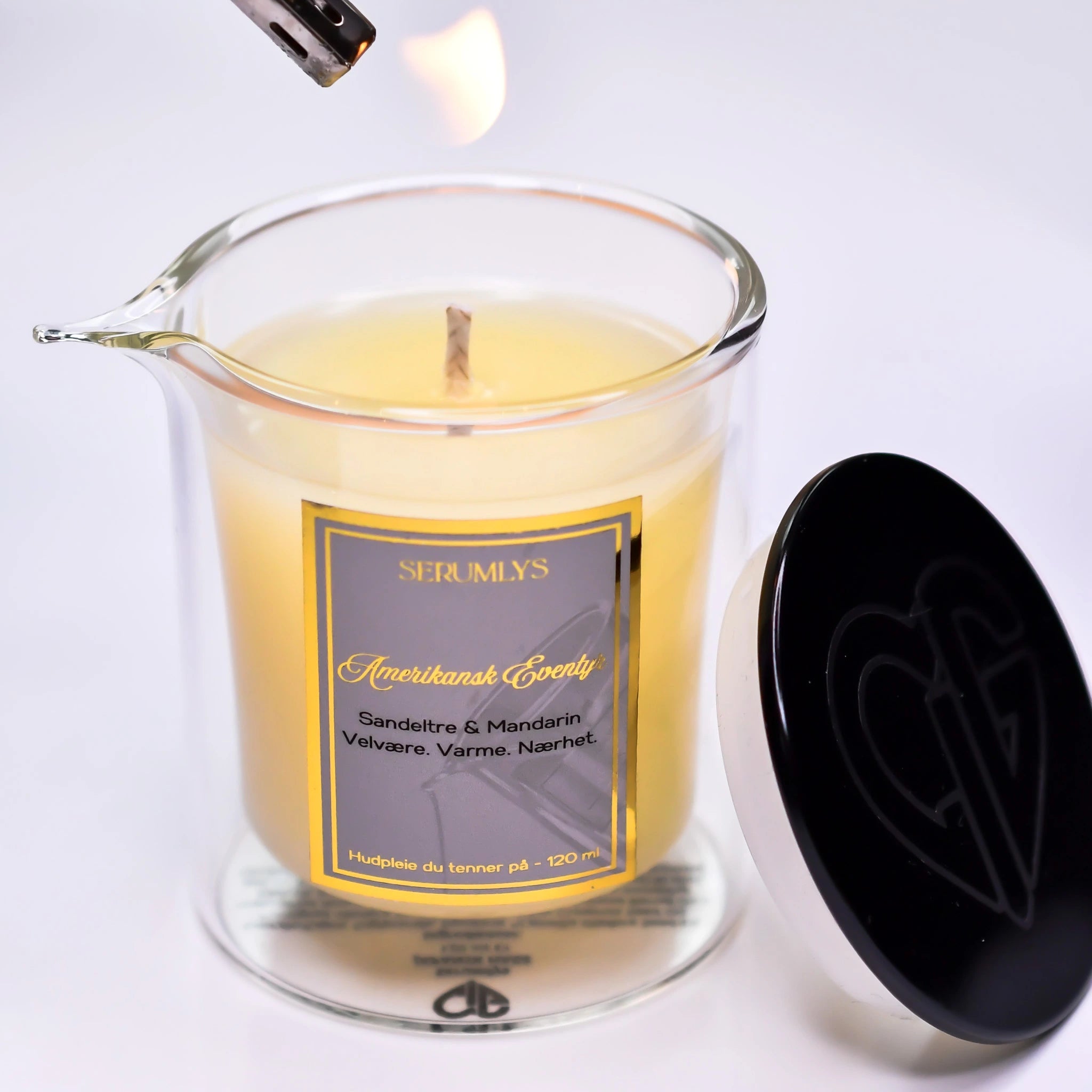 Et glass med helletut og body serum. Lyset er i ferd med å tennes med en lighter. Etter 15-20 minutter er lyset smeltet til et næringsrikt og pleiende kroppsserum. Helles direkte fra glasset og kan brukes på hele kroppen. Et produkt som gir en opplevelse på sitt eget bad. Ved siden av glasset står lokket med sort farge. Denne maskuline varianten heter Amerikansk eventyr som har en mild duft av sandeltre og mandarin.