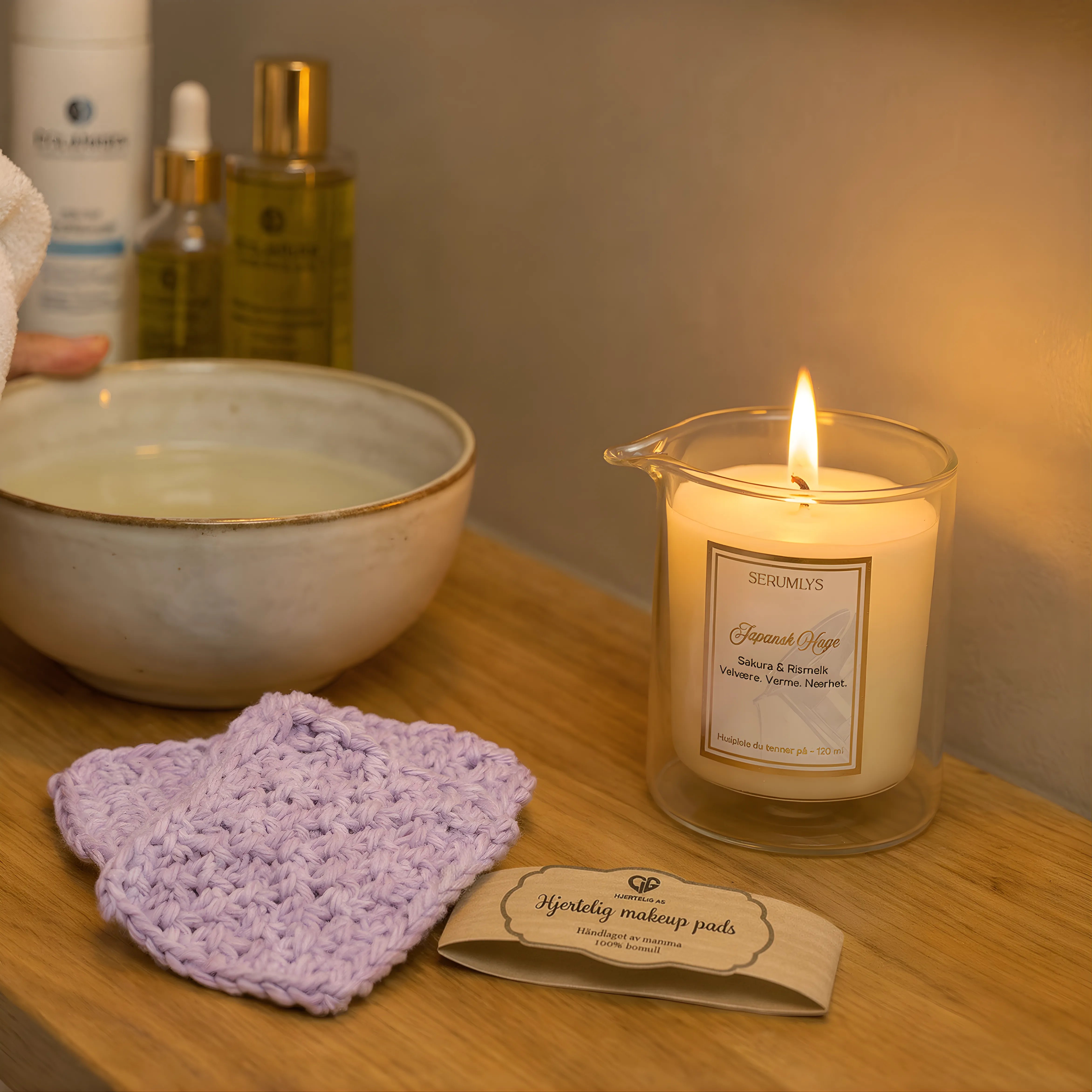 Sminkefjerner makeup pads i fargen lys lilla. Her kan man se de sminke vaskeklutene ligger på bordet klar til å bli brukt. De er tatt ut av forpakningen og serumlys naturlig hudpleie spa lyset er tent. Her er det gjort klart for en fantastisk spa kveld hjemme på egent bad med naturlige produkter som huden din vil elske. 