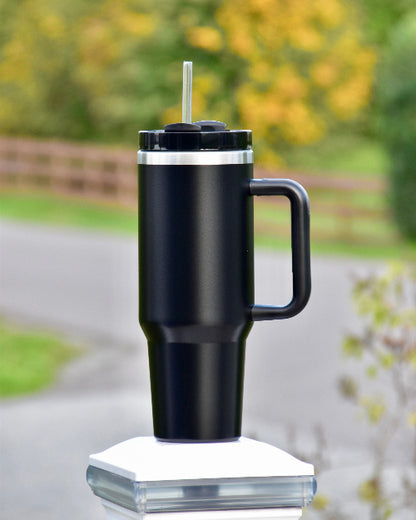 Sort tumbler med sugerør og håndtak. Passer perfekt i koppholder i de fleste biler. 1,2 liter med drikke som med god isolasjon som holder varmen eller kulden på drikken inne. Kan lasergraveres. Designet i Norge. Personlig tekst på koppen gir den et unikt preg og er perfekt om man ønsker å gi bort en termokopp i gave. 