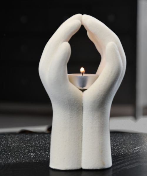 Telysholder formet som to hender som holder et telys. Telyset er tent, og man kan føle roen denne telys holderen gir når telyset lyser opp inni hendene. Dette er en ganske tung telysholder da den er laget av keramikk. 