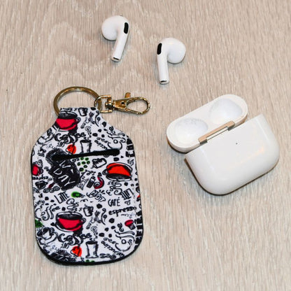 Veske til airpods på gulvet. Vesidenav ligger det airpods som er tatt ut av vesken. 