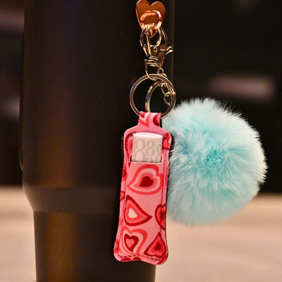 Veske til lipstick med hjertemotiv som henger på tumbleren sammen med en turkis dusk