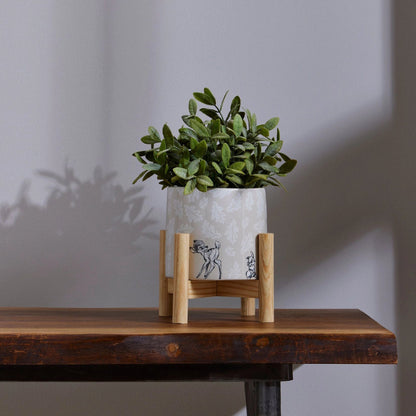 Disney potteplante med grønn blomst. Står på et stativ som står oppå et brunt bord. Gi hjemmet ditt litt Disney magi med bambi og trampe. Små detaljer som gjør en stor forskjell i hjemmet. Barndomsminner og gode stunder sammen med bambi og trampe. 