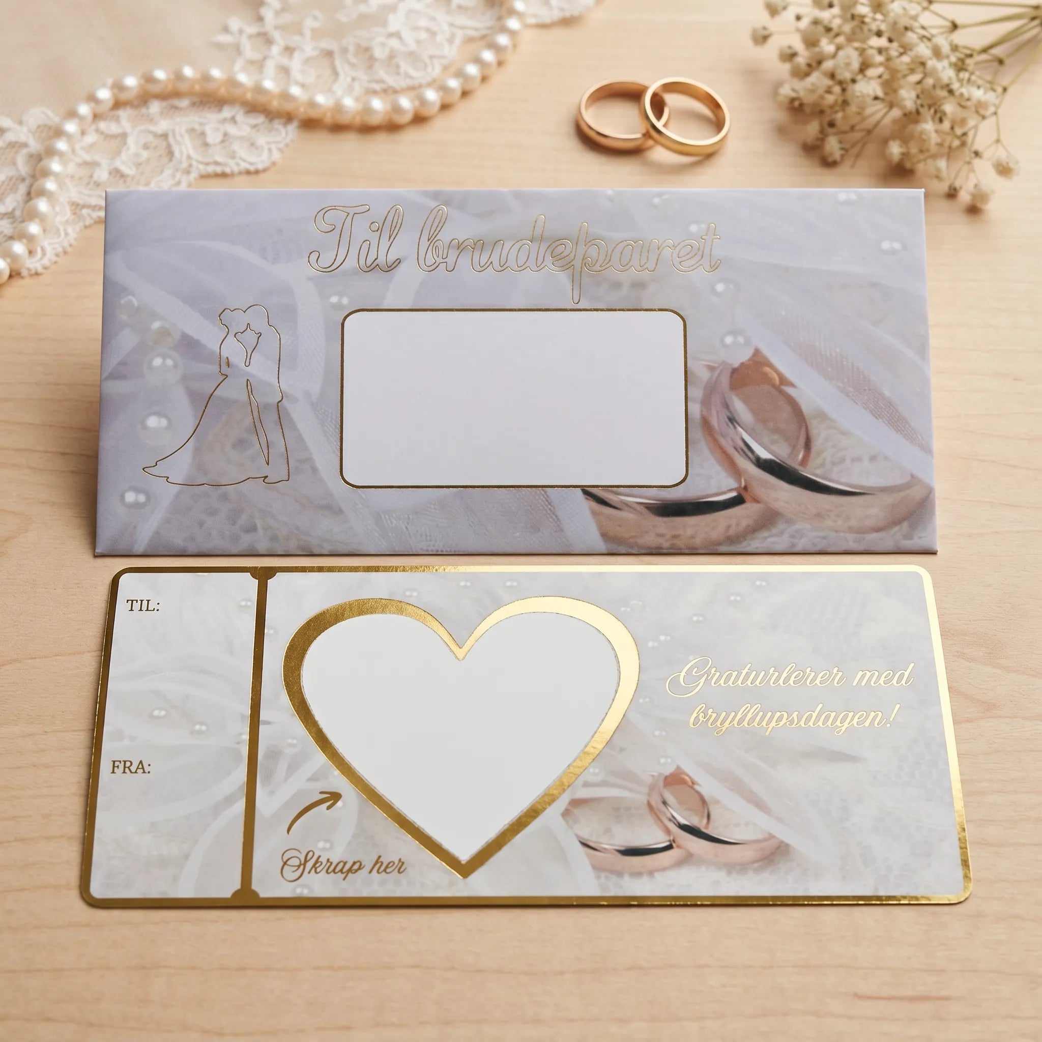 Et bryllupskort med et hvitt felt i hjerte. Skriv inn gaven du vil gi og fest over skrapelappen som følger med produktet. Perfekt til alle slags gaver, uansett om du gir penger, en opplevelsegave, eller noe helt annet. Gullfoliert tekst og kanter. Bak kortet er en elegant konvolutt som følger med produktet. Kort og konvolutt er håndlaget av Hjertelig AS.