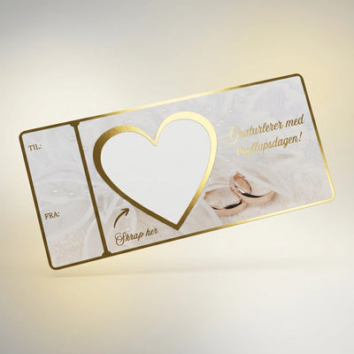 Et bryllupskort og bryllupsgave. Skriv inn gaven du vil gi i det hvite hjerte feltet. Bruk medfølgende skrapelapp og fest den over teksten din. La brudeparet skrape frem gaven. Kortet er designet med nydelig bryllupstema, med gullfolierte kanter og tekst. Håndlaget kort fra Hjertelig AS