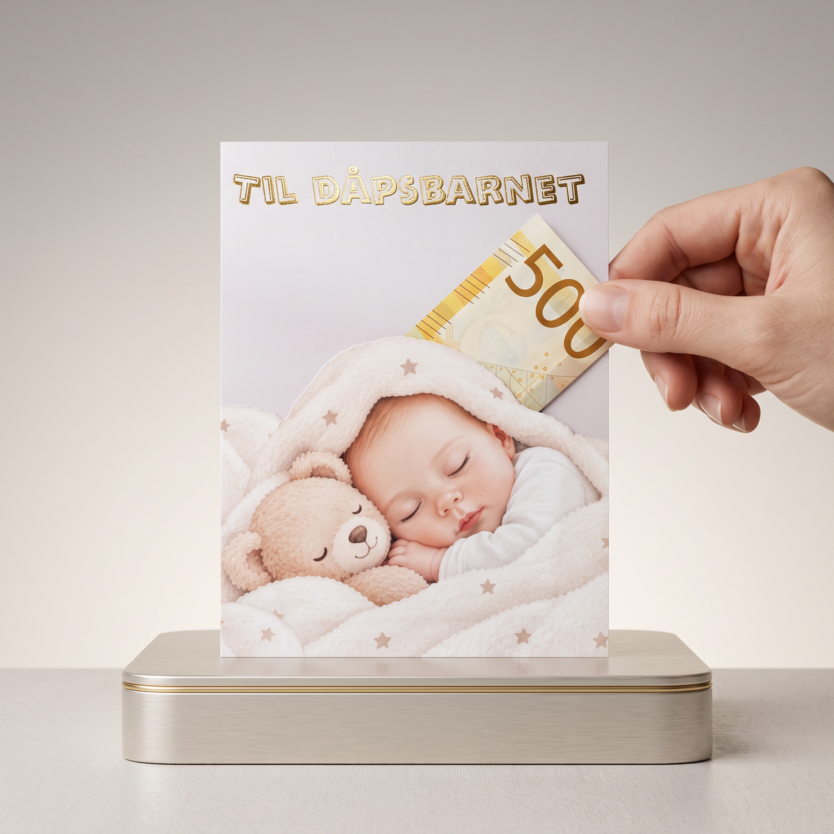 Dåps gave i et kort med nydelige gulldetaljer og en baby som ligger å sover under teppe sitt med bamse. 500kr er plassert i pengelommen som er bak babyen. en hånd strekkes ut for å ta 500 lappen. 
