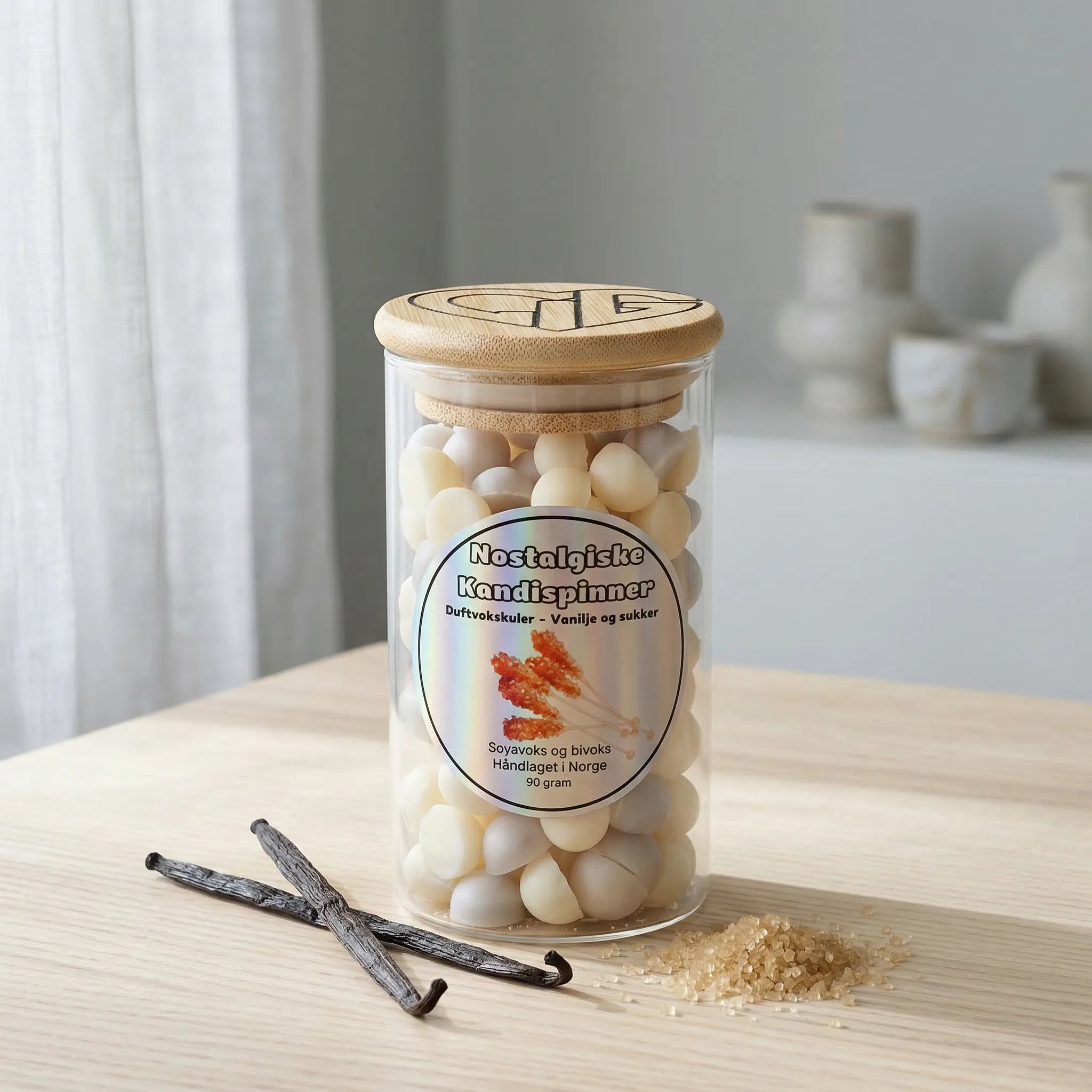 Duftvoks i glass på et bord. Ved siden av vanlijestang og brunt sukker, som illustrerer duften til nostalgiske kandispinner. Håndlaget i norge med soyavoks og bivoks. Hvert glass inneholder 90g voks.