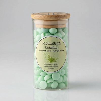 Et glass med grønn duftvoks. Forbudt på søndag har duften av nyklipt gress. Hvert glass inneholder 90g voks av soya og bivoks. Håndlaget i Norge med kjærlighet. Glasset har et bambuslokk med Hjertelig AS sin logo