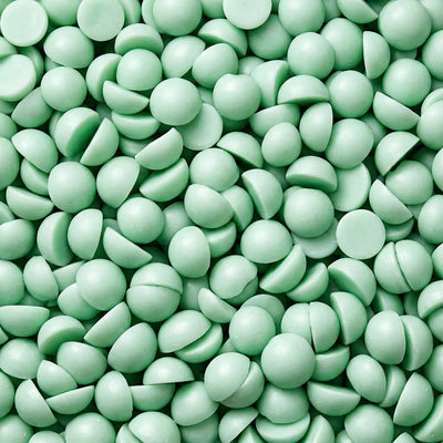 Nærbilde av små duftvokskuler i grønn farge. Tilhører duftvoksen "Forbudt på søndag" som har duft av nyklipt gress. Små halvkuler, håndlaget i norge.