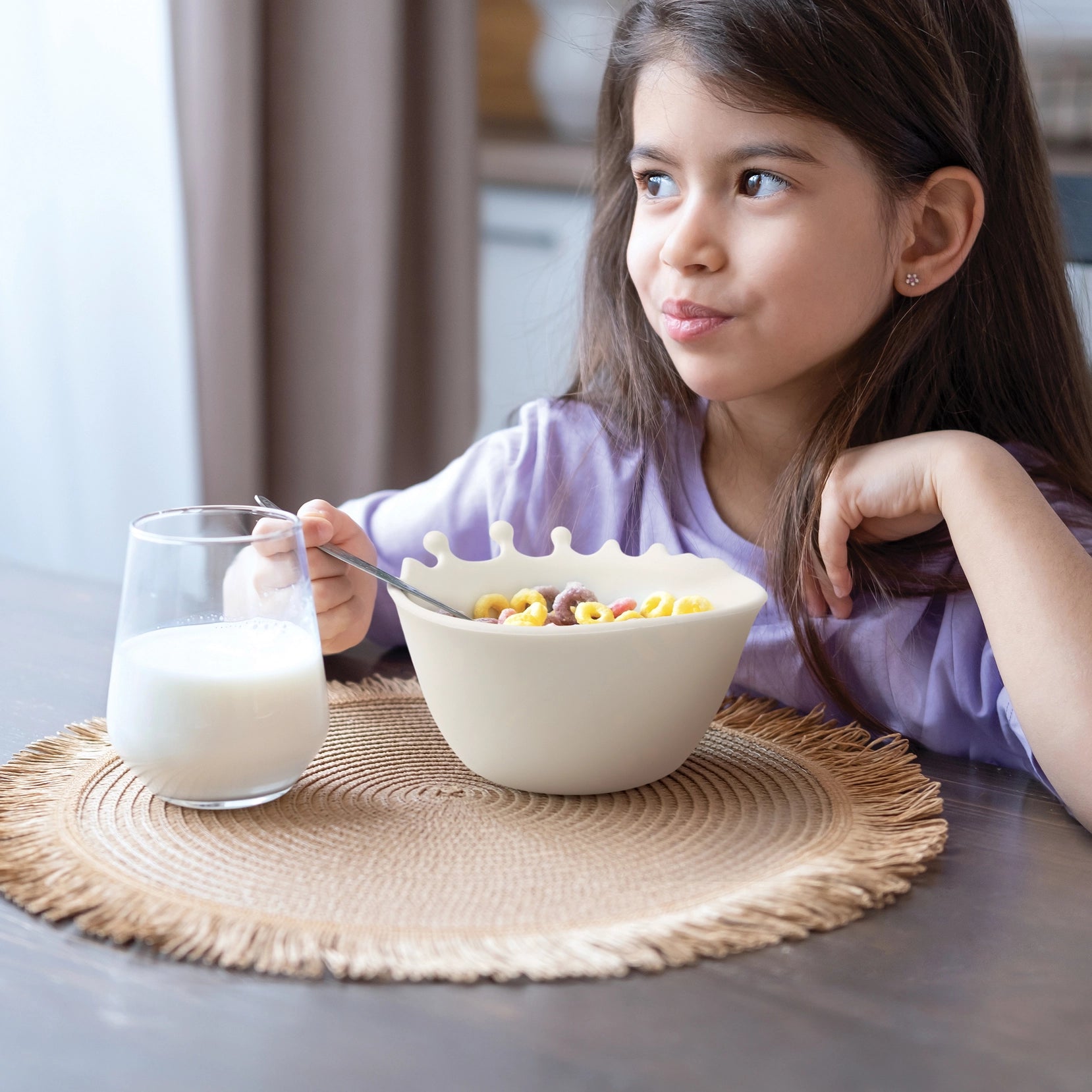 Jente som spiser frokostblanding av en designbolle, der melken ser ut til å sprute over kanten