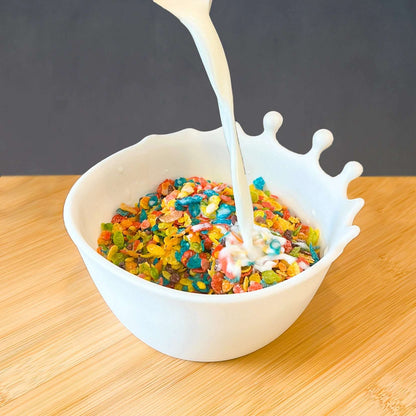 Frokostbolle som fylles opp med melk, der det ser ut som at melken spruter over kanten.