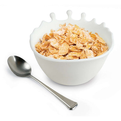 En frokostbolle i slikon. Designet viser melk som sputer opp mot kanten av bollen. I bollen ligger det frokostblanding som ser ut som corn flakes, og en sølvskje ved siden av.