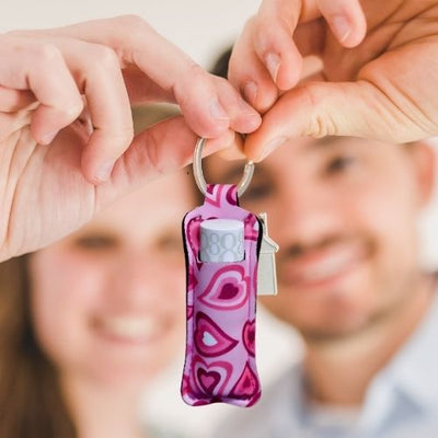 En mann og en kvinne som viser frem en nøkkelring til leppestift. Nøkkelringen har rosa hjerter som design