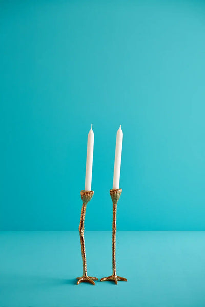 to lysestaker med strutseben i gull med to hvite stearinlys. Blå bakgrunn. Tenn lysene og hjemmet ditt vil føles både morsomt, lukseriøst og skille seg ut . Detaljene på beina gjør at de ser veldig ekte ut. 