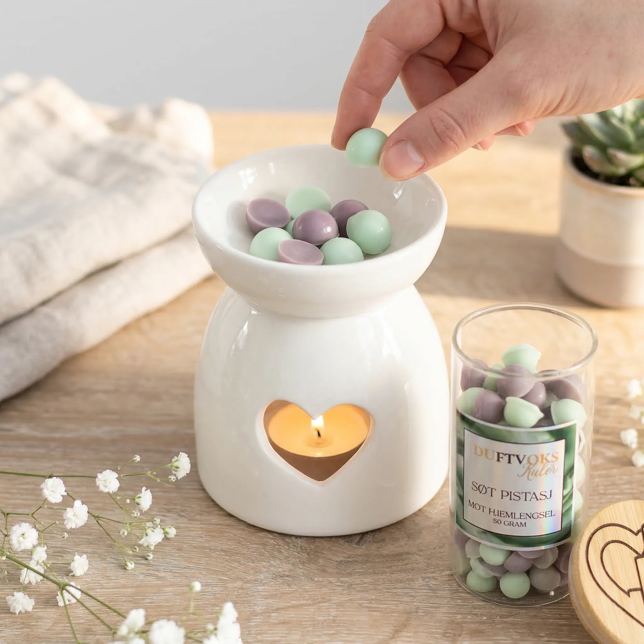 En duftbrenner der det legges i duftvokskuler av søt pistasj. En duft som skal virke lindrende mot de som har hjemlengsel. Når duftvoksen smelter i duftbrenneren, så gir det rommet en god duft som varer lenge. Duftvoksen kan brukes flere ganger før den byttes ut med ny.