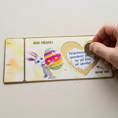 Et gavekort med skrapefelt som skrapes med et kronestykke. Kortet har gullfolierte kanter og teksten God påske og skrap her med en pil som peker mot skrapefeltet. Skriv inn det du ønsker og fest over skrapelappen som følger med kortet. Håndlaget i Norge, og er en personlig og koselig gave å gi.