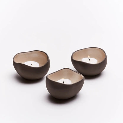 Tre telysholdere med telys som brenner. Når telysene er tent gir dette en ro til kropp og sjel. Håndlaget av keramikk i frankrike. Hver telysholder er derfor unik og spesiell. 