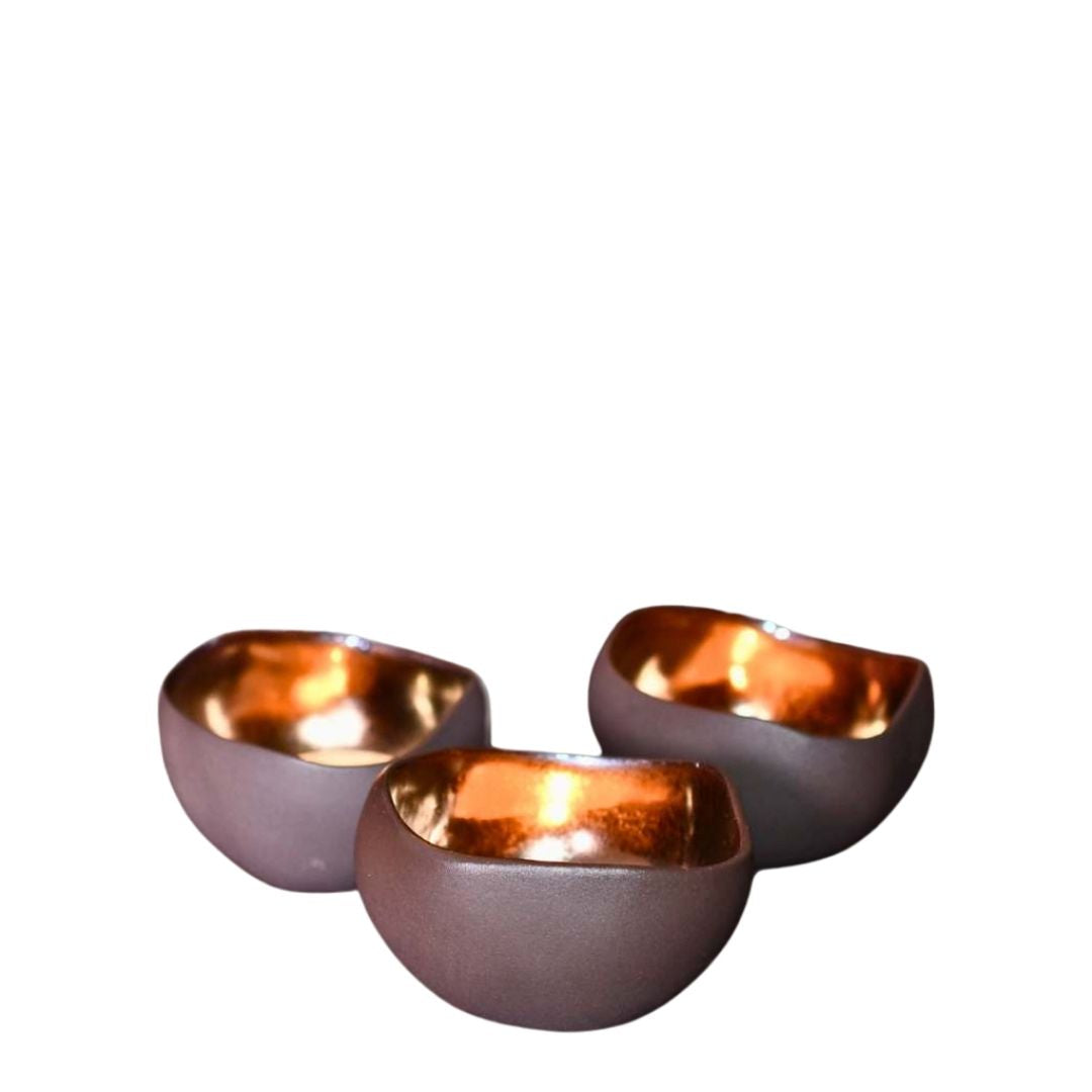 Tre håndlagde telysholdere i keramikk i brun farge og en innside med skinnende messing