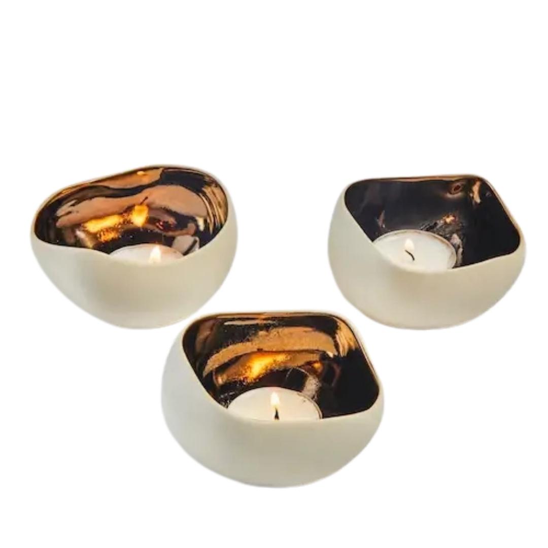 Tre håndlagde telysholdere i keramikk med en kremhvit utside og bronse innvendig