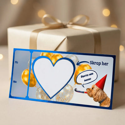 Bursdagskort med blå folie og en hund som feirer og sier "grattis med dagen". I bakgrunnen er det bursdagsfest med kake og ballonger. Bursdagsgaven må skrapes fram med en mynt akkurat som med flakslodd, og når hjertet er skrapt bort så kan man lese hva man fikk i gave. Morsom og unik måte å gi bort bursdagsgave på som man ikke får gitt fysisk der og da. 