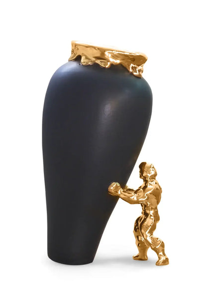 En superhelt som støtter en sort vase med gullkant. Håndlaget keramikk fra nederland. Superhelten støtter opp vasen som er i ferd ved å falle over. Et kunstverk og nydelig vase i sort farge. Toppen og superhelt i gull