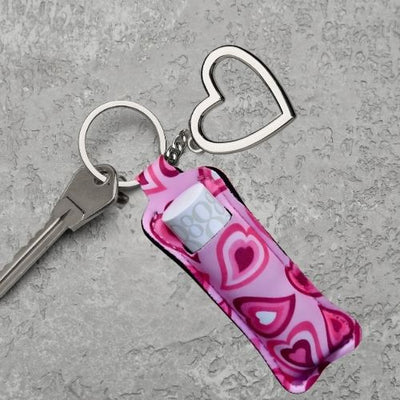 Et nøkkelknippe med en nøkkel og en rosa veske til leppestift, samt et hjerte i metall.